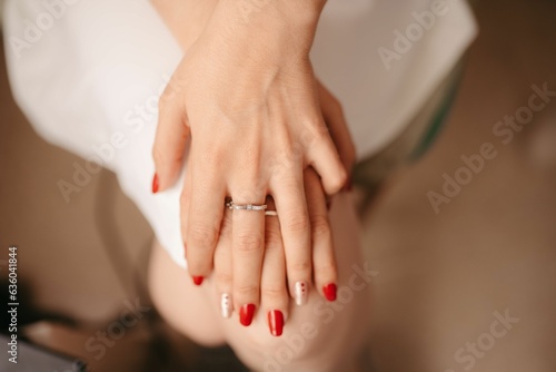 a person wearing a ring sits down with their hands on the side of her knee