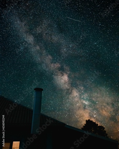 the milky is shining brightly over the stars above a small house