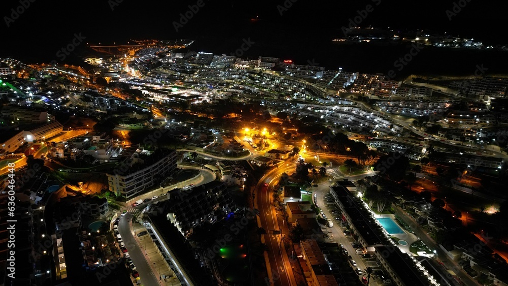 city lights are illuminating from a tall building overlooking a wide beach city lights are illuminating from a tall building overlooking a wide beach
