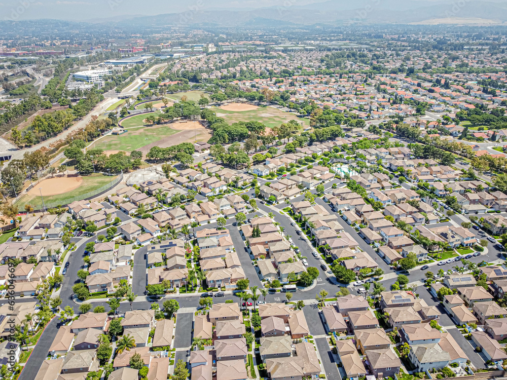Irvine, California, USA – August 14, 2023: Top drone view toward Irvine townhouses townhomes above Harvard Community Park along with Jamboree Rd