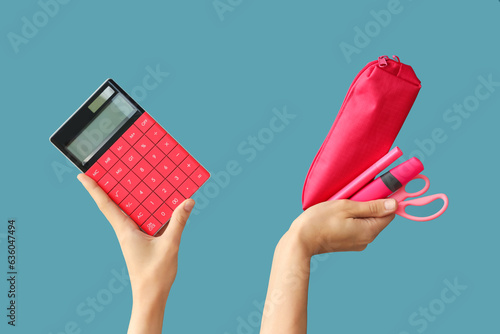 Female hands holding school supplies and calculator on blue background