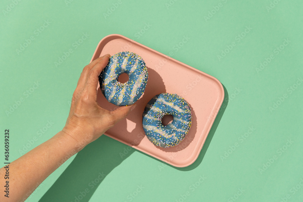 Hand grabbing pastel color donuts Hand grabbing pastel color donuts