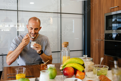 men eating yogurt for healthy breakfast in the kitchen