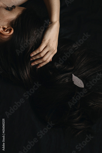 Close Up long woman's black hair with white leaf and fingers photo