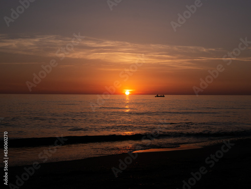 Sunset in Italy Toskana at mittelmeer with fishing boat in the water and small Waves Dawn