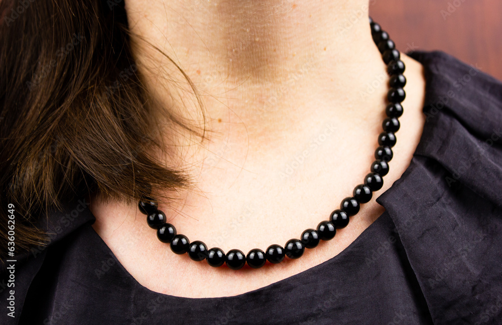 Black necklace on a woman. Women's black jewelry. Round black beads on a woman.