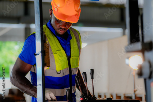 Factory engineer African man checking and reparing mahine at heavy factory.Worker works at heavy machine at industry factory. with machinery equipment plant technology. photo