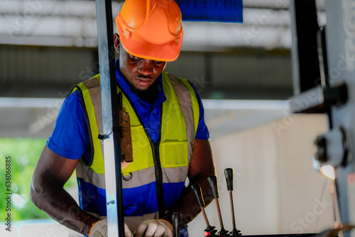 Factory engineer African man checking and reparing mahine at heavy factory.Worker works at heavy machine at industry factory. with machinery equipment plant technology. photo