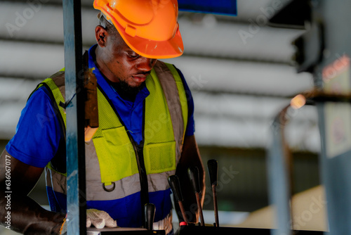 Factory engineer African man checking and reparing mahine at heavy factory.Worker works at heavy machine at industry factory. with machinery equipment plant technology. photo