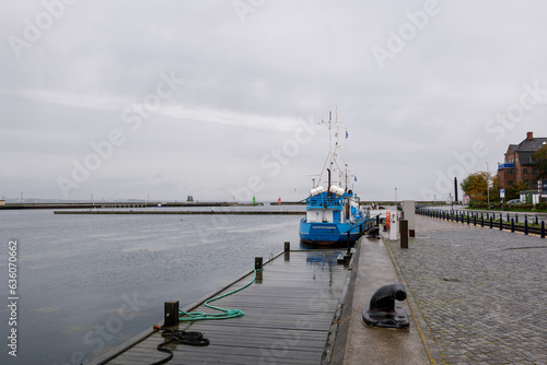 Outdoor scenery on the promenade waterfront and pier with sailing boat anchor against overcast sky in Helsingor, Denmark.