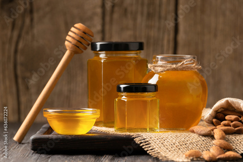 Honey in bowl, dipper and yellow flowers on an aged wooden background.