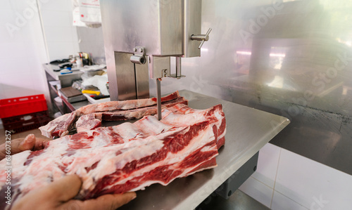 Crop butcher cutting meat with band saw photo