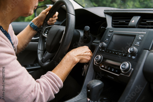 middle aged woman turning key in ignition  photo