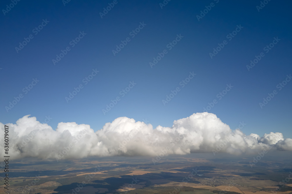 Aerial view from airplane window at high altitude of earth covered with white puffy cumulus clouds Aerial view from airplane window at high altitude of earth covered with white puffy cumulus clouds