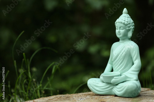Decorative Buddha statue on stump outdoors  space for text