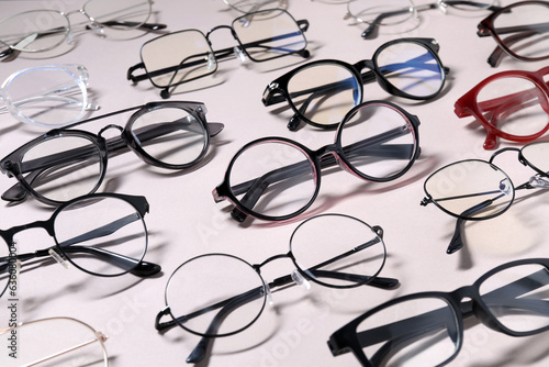 Many different stylish glasses on light grey background, closeup