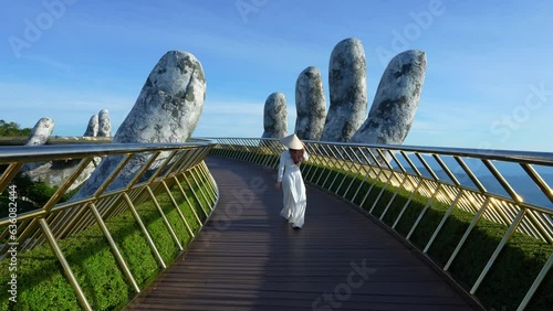 4k slow motion,Asian woman wearing white.Vietnamese culture with traditional conical hat withon the Golden han Bridge, Da Nang City, Vietnam. photo