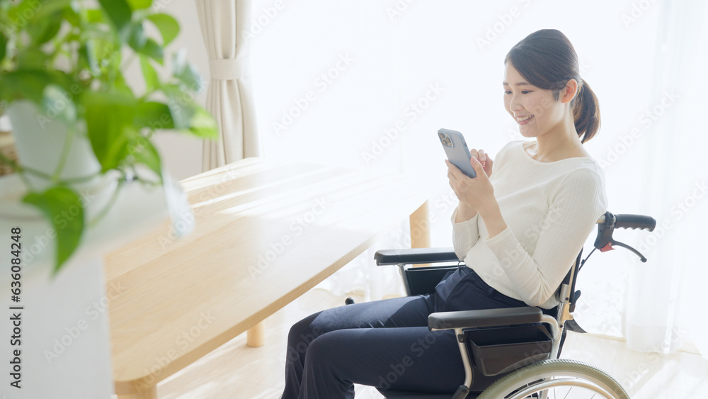 車椅子に乗るスマホを使う女性 車椅子に乗るスマホを使う女性