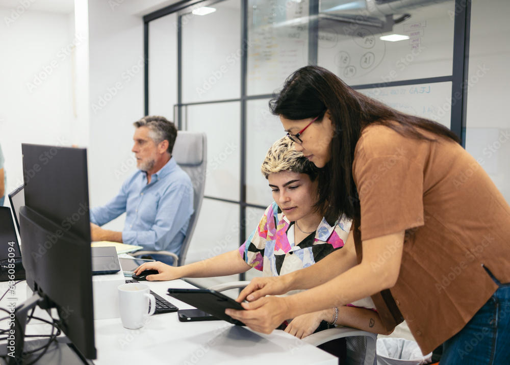 Mature Asian woman and young non-binary person working in office Mature Asian woman and young non-binary person working in office