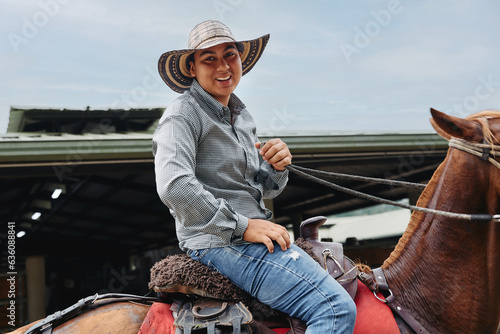 Smiling cowboy portrayed riding on his horse on a Colombian farm photo