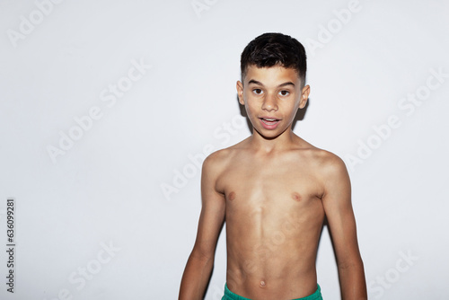 Twelve year old boy without a shirt looking at camera photo