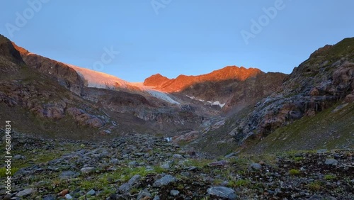 timelpase of a orange glowing sunrise in remote high alpine area over a huge glacier photo
