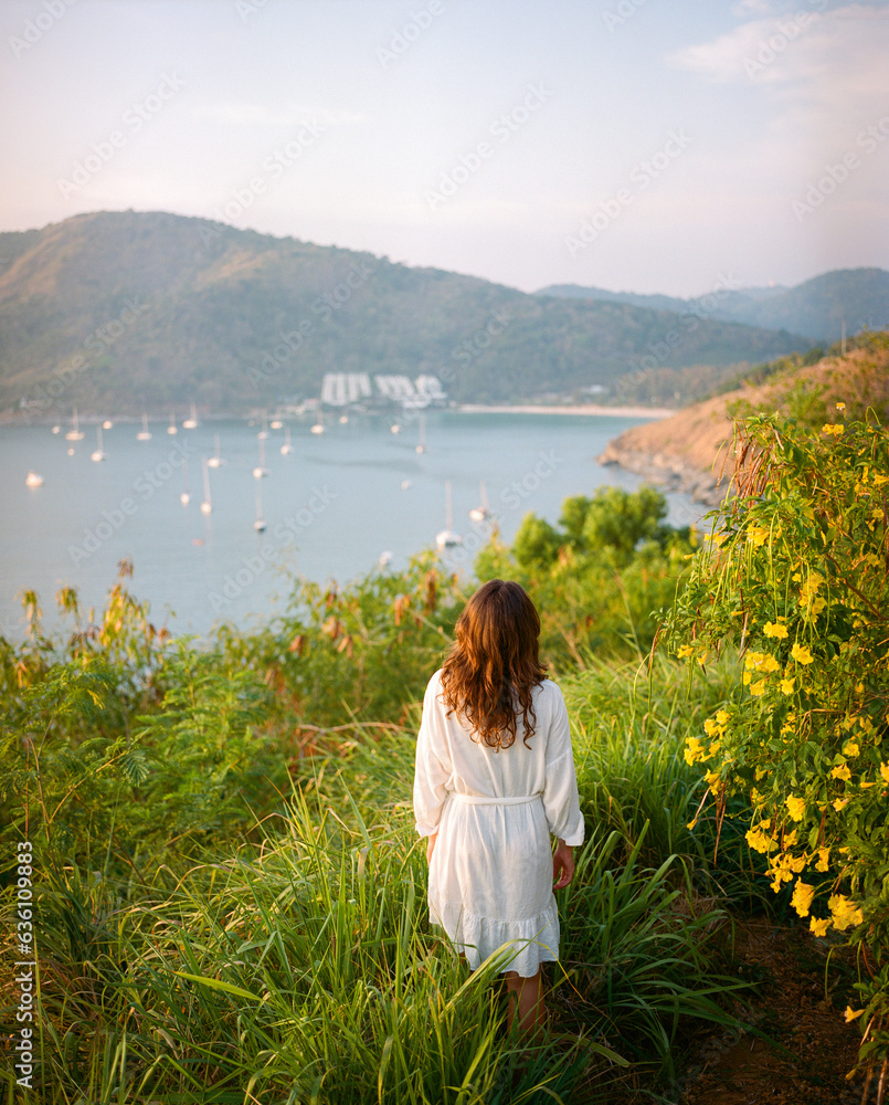 © Anna Tsukanova/Stocksy - Elegant woman in white dress standing on the background of the sea