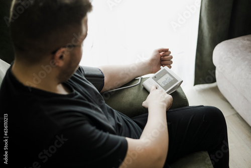 Young man Measures Blood Pressure At Home photo
