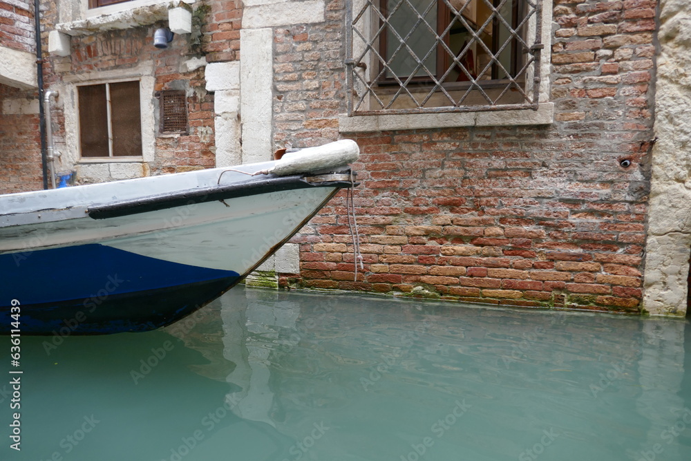 Venice canal with flooded side of building and front of floating boat in water