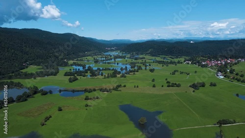 Aerial panorama view showing intermittent lake named Cerknica surrounded by green mountain landscape with blue sky in summer - Slovenia, photo
