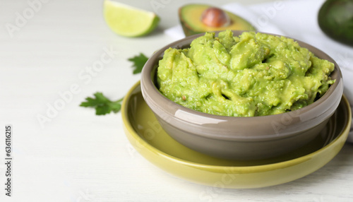 Bowl with delicious fresh guacamole on white table, closeup. Space for text