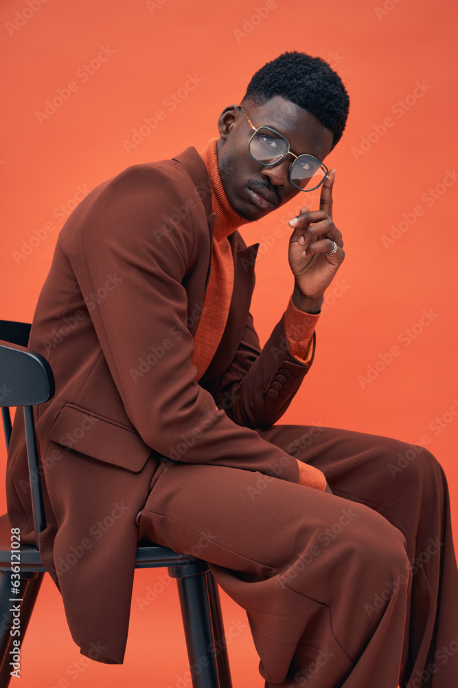 © Elena Kharichkina/Stocksy - Fashionable male model in brown suit posing in studio