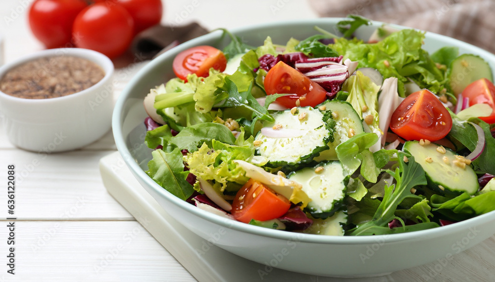 Delicious salad in bowl on white wooden table, closeup