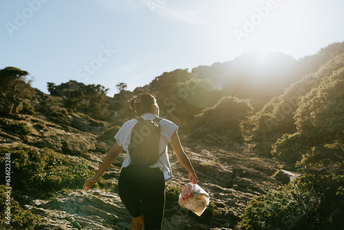 Woman Carrying Trash in Rocky Landscape photo