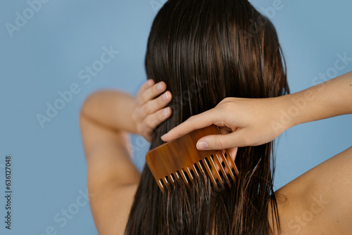 Woman brushing wet hair with comb.