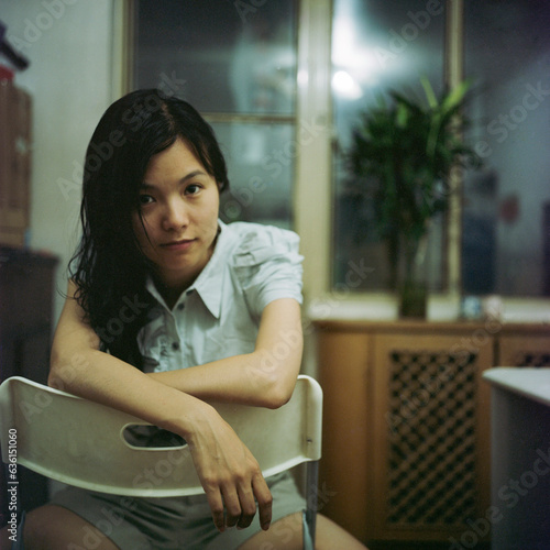 The woman sat in the room with her hands on the back of the chair