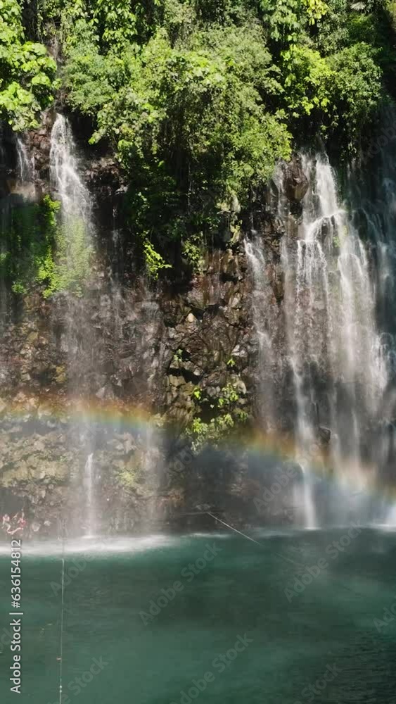 Waterfall and rainbow in the tropical mountain jungle. Tinago Falls. Mindanao, Philippines. Travel concept. Vertical video. Waterfall and rainbow in the tropical mountain jungle. Tinago Falls. Mindanao, Philippines. Travel concept. Vertical video.