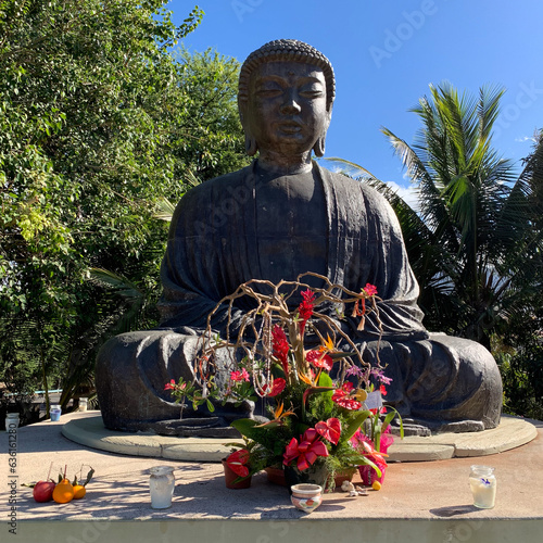 Flowers at the feet of the Buddha statue at the Jodo Buddhist Temple in Lahaina, Maui, Hawaii  photo