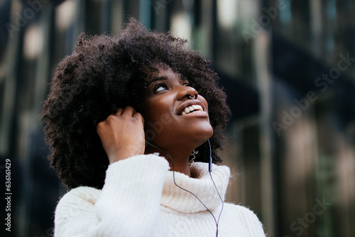 Happy black woman in earphones listening to music on smartphone photo