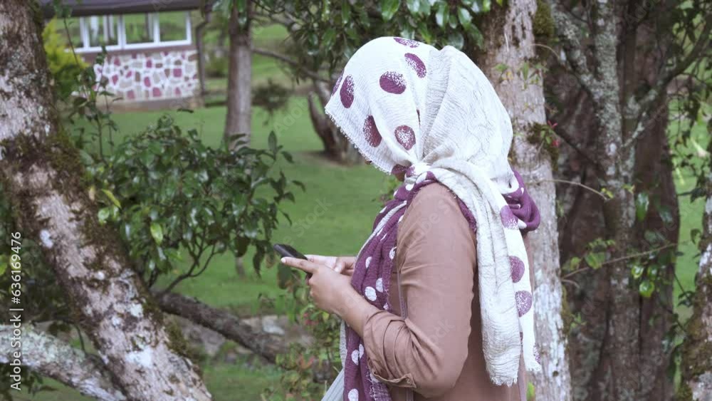 Harmony of Nature and Communication: Muslim Women in Scarves Using Smartphones at the Park Harmony of Nature and Communication: Muslim Women in Scarves Using Smartphones at the Park