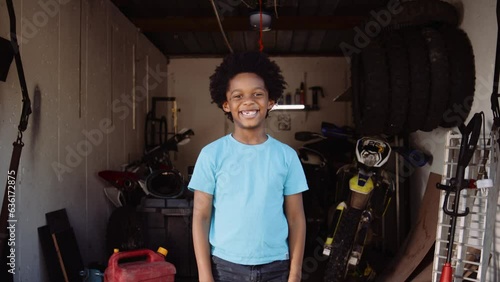 Wide portrait young boy smiling at camera in home bike workshop in garage photo