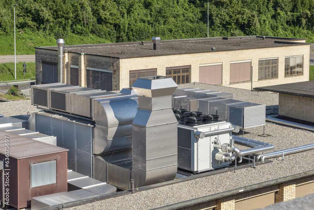 hvac ventilation system on a roof in front of a industrial building, chiller and cooler next to a monobloc hvac ventilation system on a roof in front of a industrial building, chiller and cooler next to a monobloc