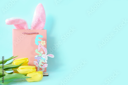 Gift card with Easter figurine, rabbit ears in a pink bag and yellow tulips. High quality photo
