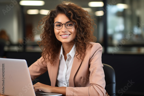 Smiling african american professional young woman in suit working in front of laptop in office