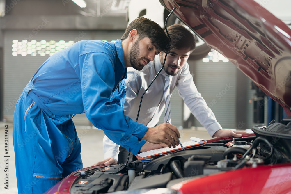 Auto check up and car service shop concept. Mechanic writing job checklist to clipboard to estimate repair quotation to client at workshop garage. Auto check up and car service shop concept. Mechanic writing job checklist to clipboard to estimate repair quotation to client at workshop garage.