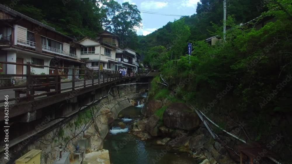 Aerial shot moves ahead, capturing the winding watercourse's path through a charming Japanese village. Aerial shot moves ahead, capturing the winding watercourse's path through a charming Japanese village.
