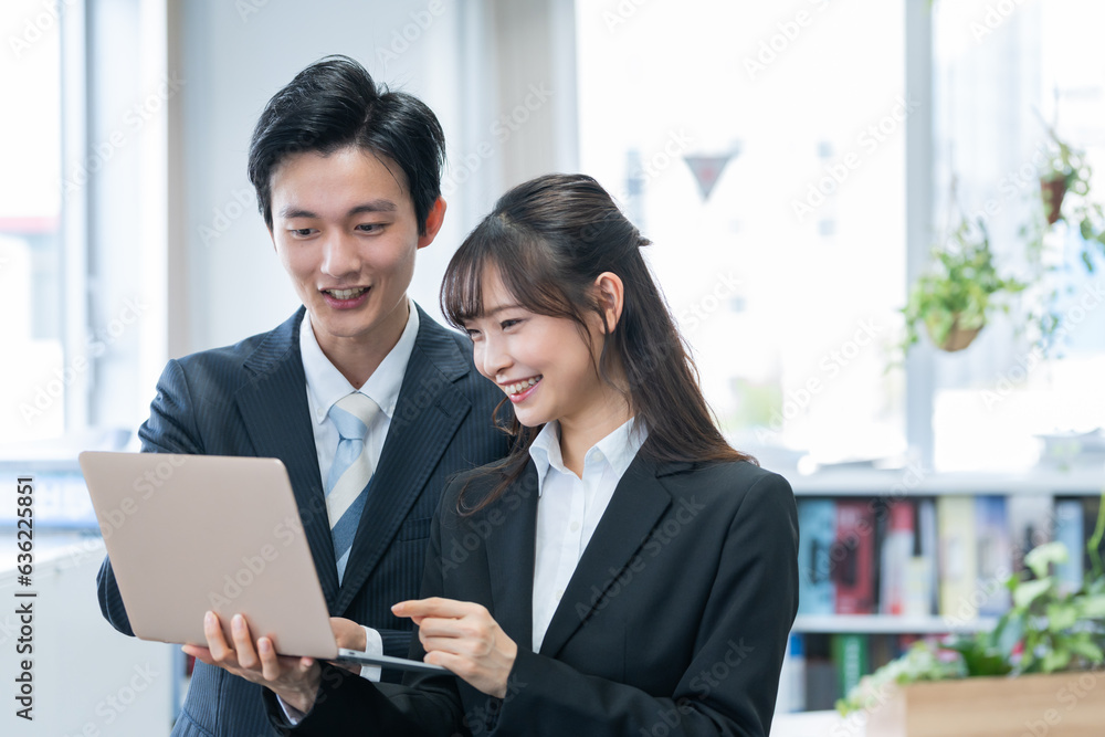 パソコンで仕事する新人ビジネスマン男女