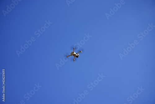 Fototapeta Naklejka Na Ścianę i Meble -  A small quadcopter hovered in the blue sky. Drone in flight.