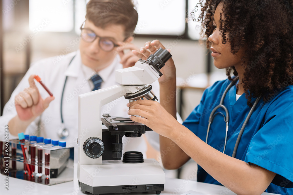 Team of blood sample tube research scientists working with a microscope for vaccine development in pharmaceutical research labeling. Team of blood sample tube research scientists working with a microscope for vaccine development in pharmaceutical research labeling.