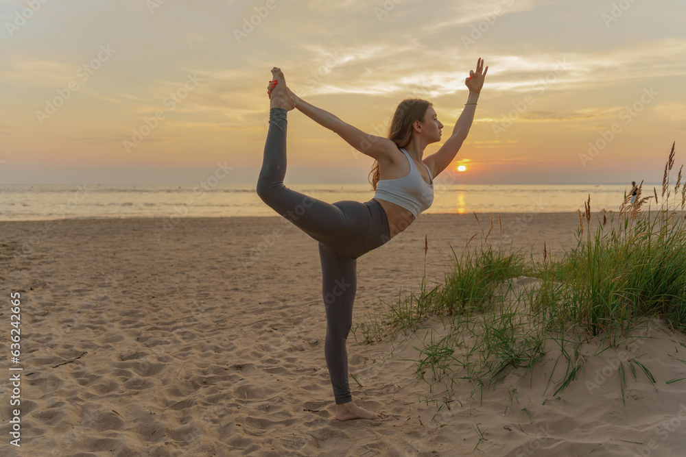 Obraz premium Meditative harmony and balance of a person, mental health. The woman is slender, flexible body, practicing yoga exercise beautiful asana. Fitness on the background of sunset.